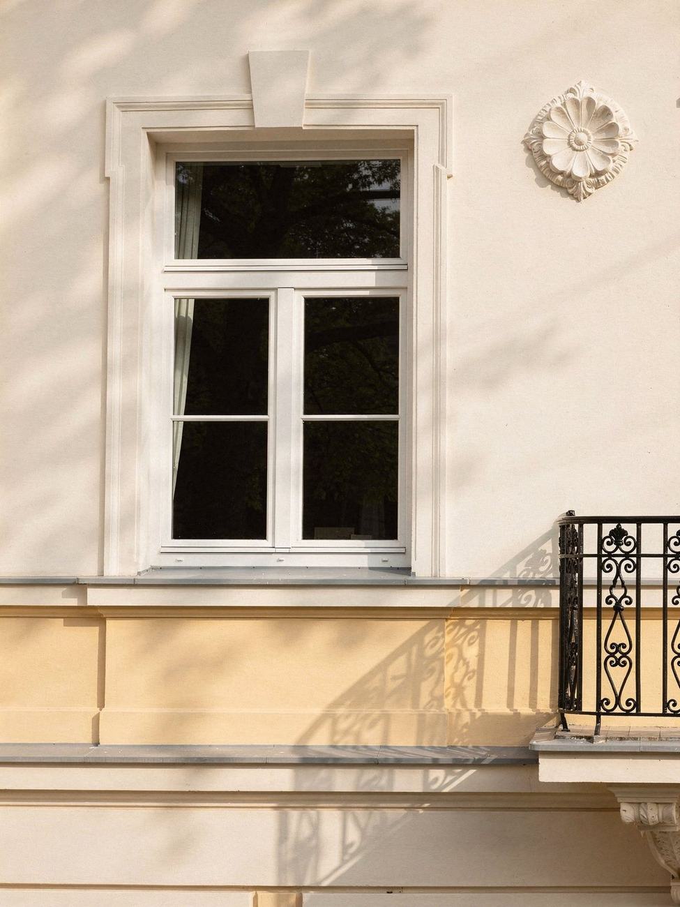 Sprossenfenster und Stuckrosette an einer hellen Villenfassade